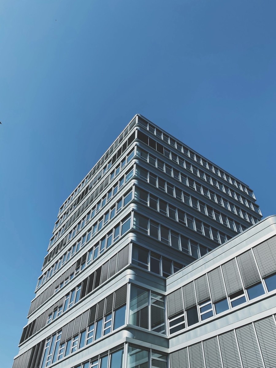 Bürohochhaus mit Metall- und Glasfassade, von unten gegen blauen Himmel fotografiert